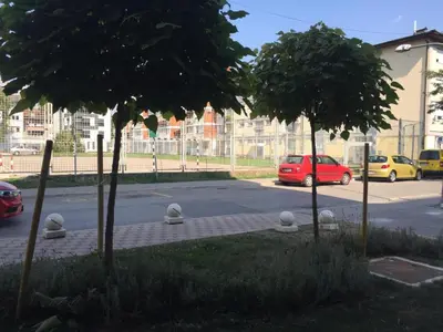 a red car parked in a parking lot with two trees at Apartment Palas in Banja Luka