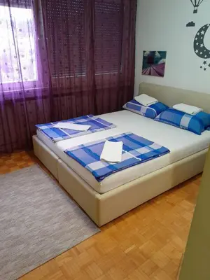 a bedroom with a bed with blue and white sheets at Apartman centar lux in Tuzla