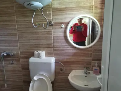 a person taking a picture in a mirror in a bathroom at Lux bungalow in Foča