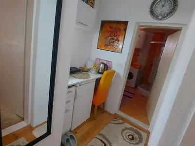 a small kitchen with a desk and a clock on the wall at Apartmani GS ***** Zavidovici in Zavidovići