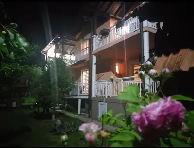 a building at night with pink flowers in the foreground at Apartmani GS ***** Zavidovici in Zavidovići