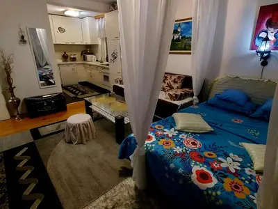 a bedroom with a blue bed and a kitchen at Apartmani GS ***** Zavidovici in Zavidovići