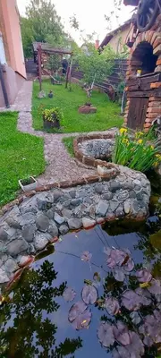 a garden with a pond with flowers and a house at Apartmani GS ***** Zavidovici in Zavidovići