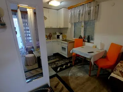 a kitchen with a table and orange chairs in a kitchen at Apartmani GS ***** Zavidovici in Zavidovići
