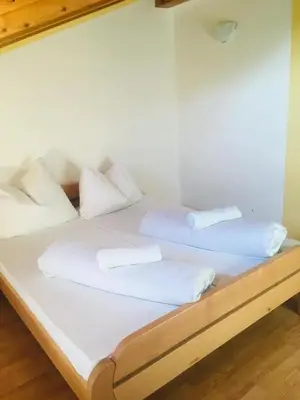a bed with white sheets and pillows on it at OMLADINSKI HOTEL ROSTOVO in Bugojno