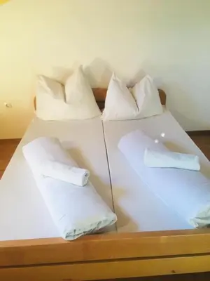 a white bed with four pillows on it at OMLADINSKI HOTEL ROSTOVO in Bugojno