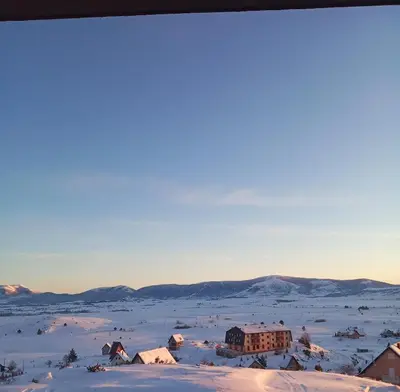 a village in the snow with mountains in the background at Apartman Panorama in Kupres