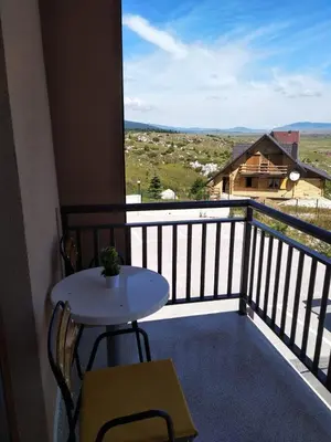 a balcony with a table and a view of a house at Apartman Panorama in Kupres