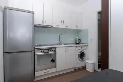 a kitchen with a stainless steel refrigerator and a washing machine at Hazam Aparthotel in Sanski most