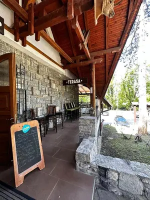 a restaurant with a stone wall and a sign on a patio at Prenoćište/Restoran Lovac in Bihać