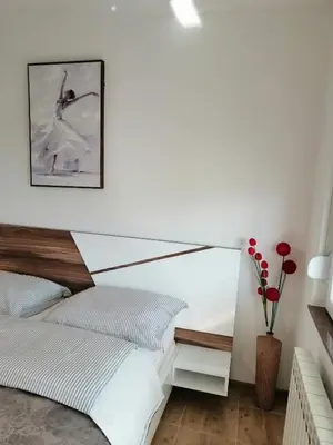 a bedroom with a bed and a white wall at Apartman EDEN No 1 in Teslić