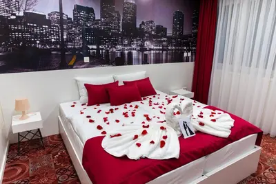 a bedroom with a bed with red pillows and white sheets at Hotel Biss in Zenica