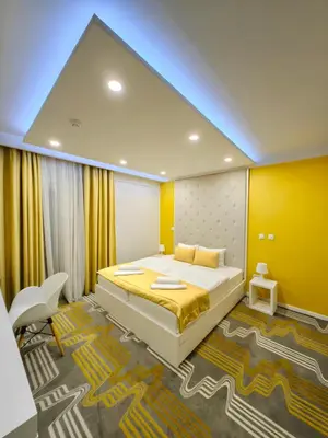 a bedroom with a large bed and a yellow wall at Hotel Biss in Zenica