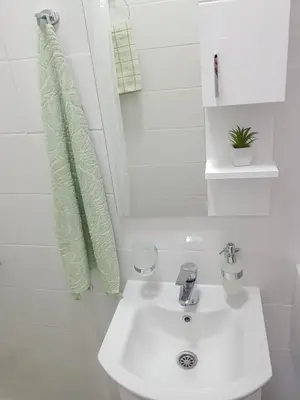 a white bathroom with a sink and a green towel at Korzo Tuzla in Tuzla