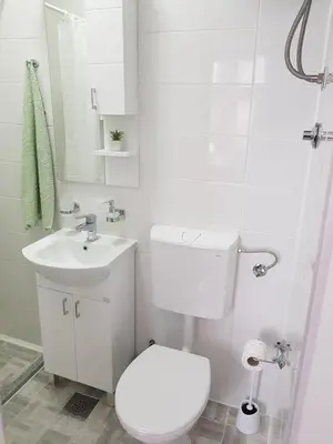a white bathroom with a toilet and a sink at Korzo Tuzla in Tuzla