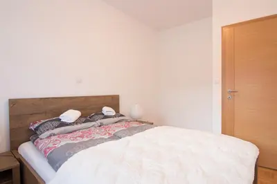 a bedroom with a white bed with a wooden headboard at Apartman Carica in Visoko