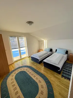 two beds in a room with a rug at Kuća Vesna in Kupres