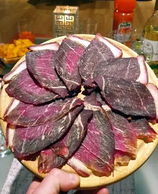 a person holding a plate of meat on a table at Bungalovi Ključ in Ključ