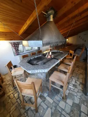 a large stone fireplace in a room with wooden ceilings at Apartmani Vila in Kupres