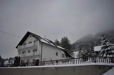 a white house with a fence in front of it at Apartmani Vila in Kupres