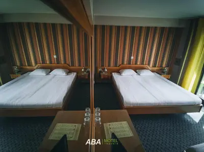 two beds in a hotel room with a table at Garni Motel Aba in Travnik
