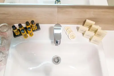 a bathroom sink with bottles of alcohol and soap at Hotel Soni Lux in Tuzla