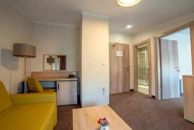 a living room with a yellow couch and a table at Hotel Soni Lux in Tuzla