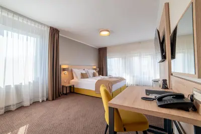 a hotel room with a bed and a desk at Hotel Soni Lux in Tuzla