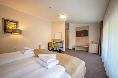 a hotel room with two beds and a desk at Hotel Soni Lux in Tuzla