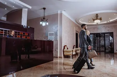 a man walking through a lobby with his luggage at Hotel Zepter Palace in Banja Luka