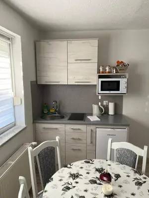 a kitchen with a table and chairs and a kitchen with a table and a microwave at Apartmani Ćurković in Kupres