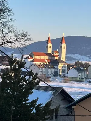 a small town with a church in the snow at Apartmani Ćurković in Kupres