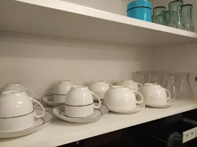 a row of white cups and saucers on a shelf at DreamHouse in Jajce