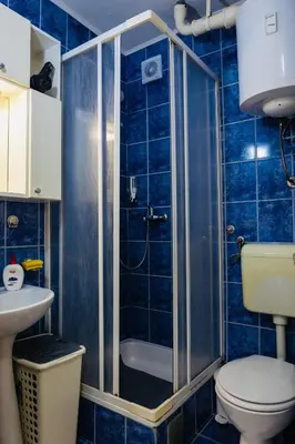 a blue tiled bathroom with a toilet and a shower at Apartman Olivia in Banja Luka