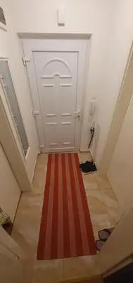 a hallway with a white door and a red stripe rug at Stan na dan Prnjavor, Gajba u centru in Prnjavor