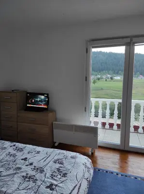 a bedroom with a bed and a television and a balcony at Vlasic holiday home in Vlasic