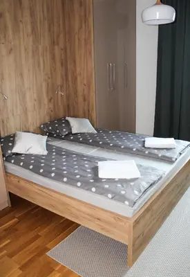 a large bed in a room with a wooden floor at Bright, modern & cozy apartment in Tuzla