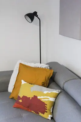 a lamp sitting on top of a couch with a pillow at Bright, modern & cozy apartment in Tuzla
