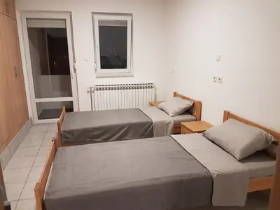 two beds in a room with two windows at DASS apartmani in Banja Luka