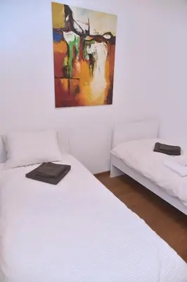 two beds in a room with a painting on the wall at Jackey apartment in Banja Luka