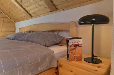 a bedroom with a bed and a book on a table at Kiwi Chalet in Kupres
