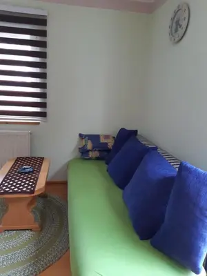 a green couch with blue pillows next to a table at Apartman Jonjić in Kupres