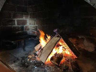 a brick oven with a fire in it at Apartmani Turalija in Kupres