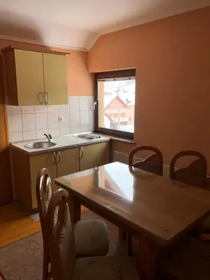 a kitchen with a table and a sink and a table and chairs at Apartmani Turalija in Kupres