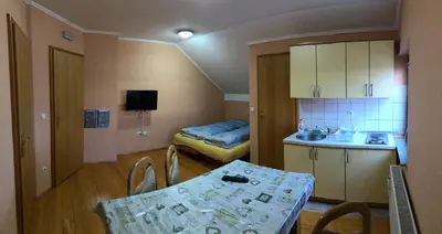 a small room with a table and a kitchen with a bed at Apartmani Turalija in Kupres