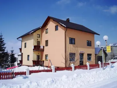 a house with a red fence in the snow at Apartmani Turalija in Kupres