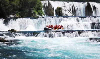 a group of people in a boat in a waterfall at Crystal Račić in Bihać