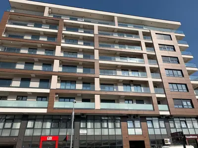 a tall building with a red sign in front of it at City Center Apartment in Banja Luka