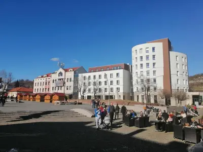 a group of people sitting in chairs in front of buildings at Apartman Viktoria in Tuzla
