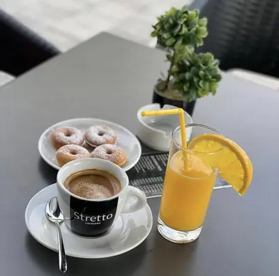 a table with a cup of coffee and a glass of orange juice at Hotel Tanja in Banja Luka